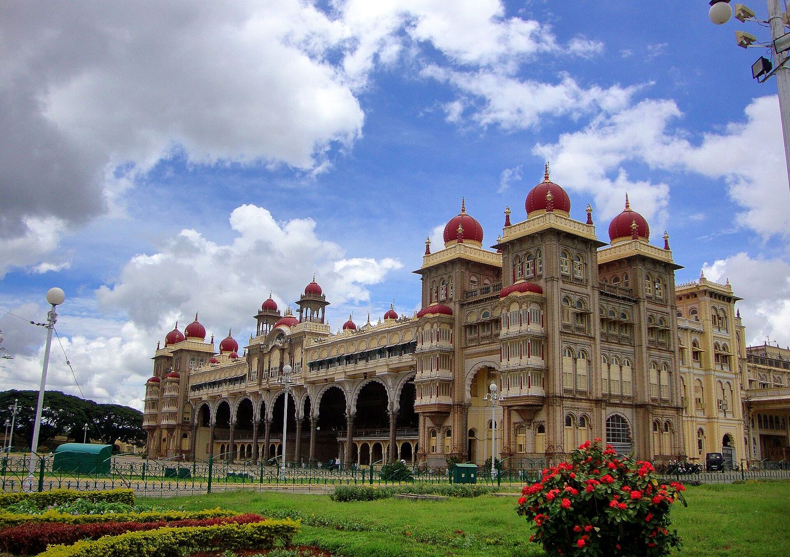 Mysuru Palace with its red domes under a blue sky full of clouds