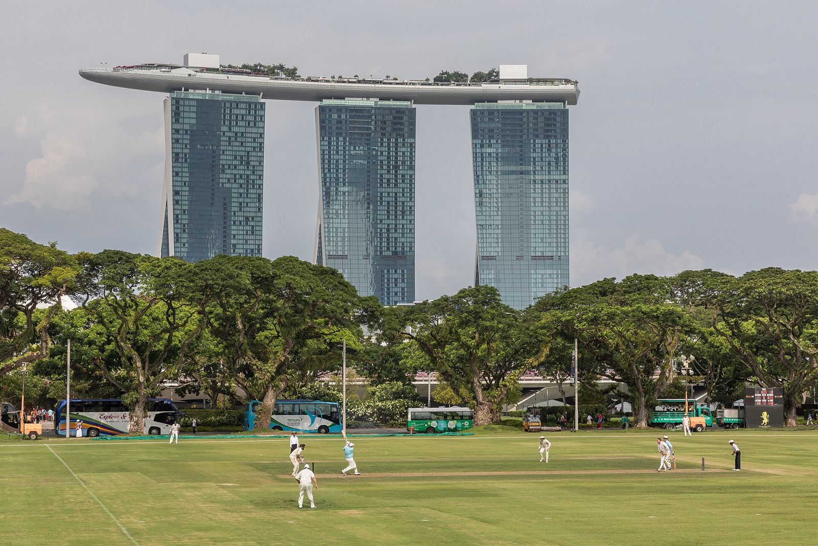 Marina Bay Sands above the trees and a cricket match on the Padang in Singapore